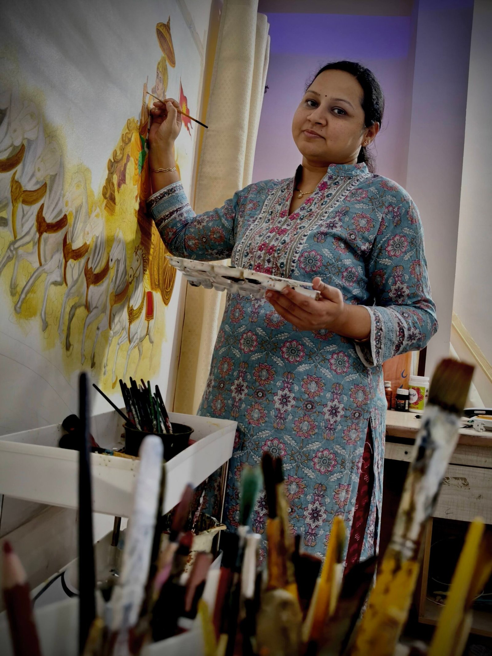 Neha Tagai Bhatt surrounded by her original paintings at an exhibition